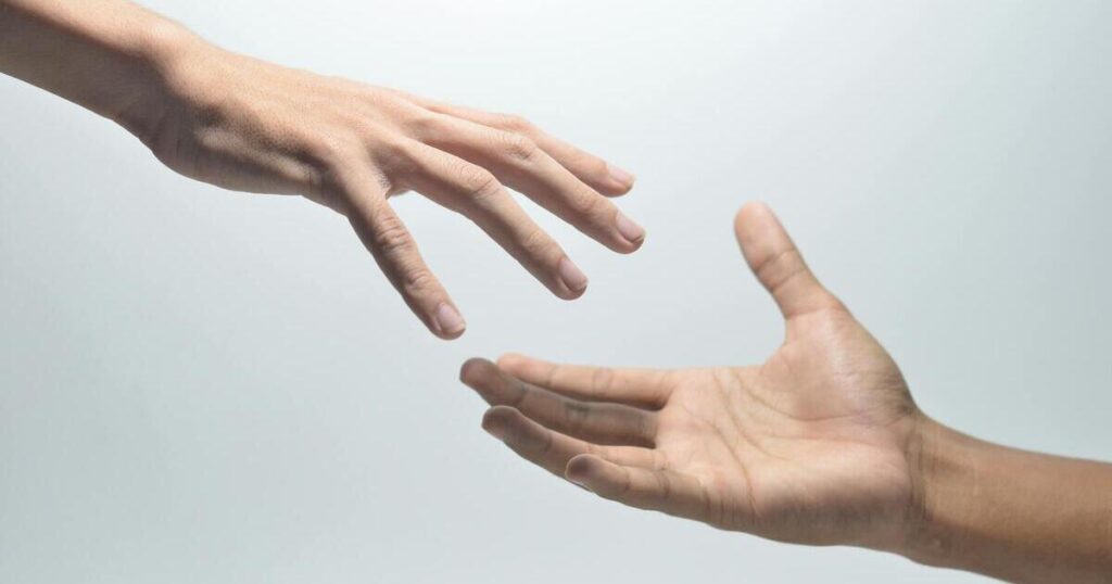 Hands reaching out to each other from either side of the image.