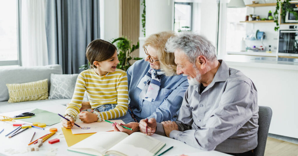 Grandparents help grandchild with her homework at home.